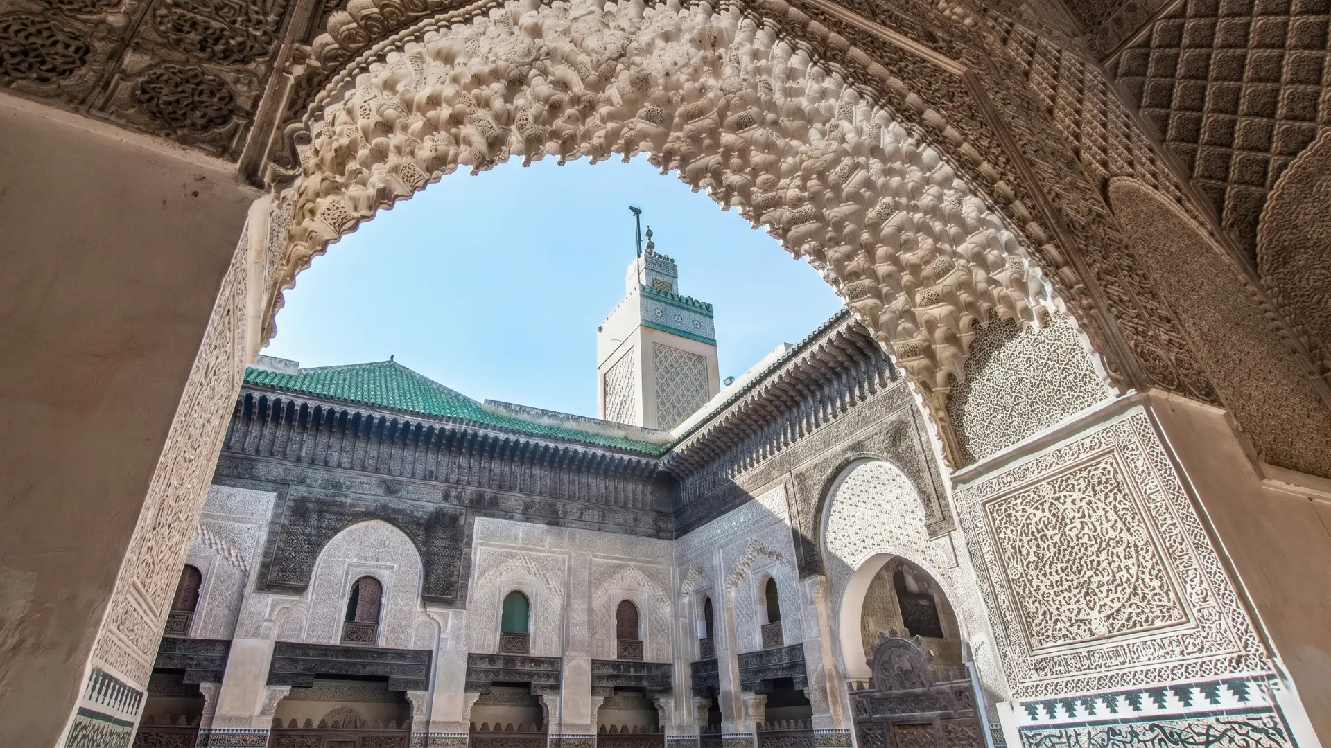 Bou Inania Madrasa Fez | Stunning Moorish Architecture & Carved Arch Detailed stone carved arch framing a green-tiled minaret and courtyard in historic Fez medersa Morocco