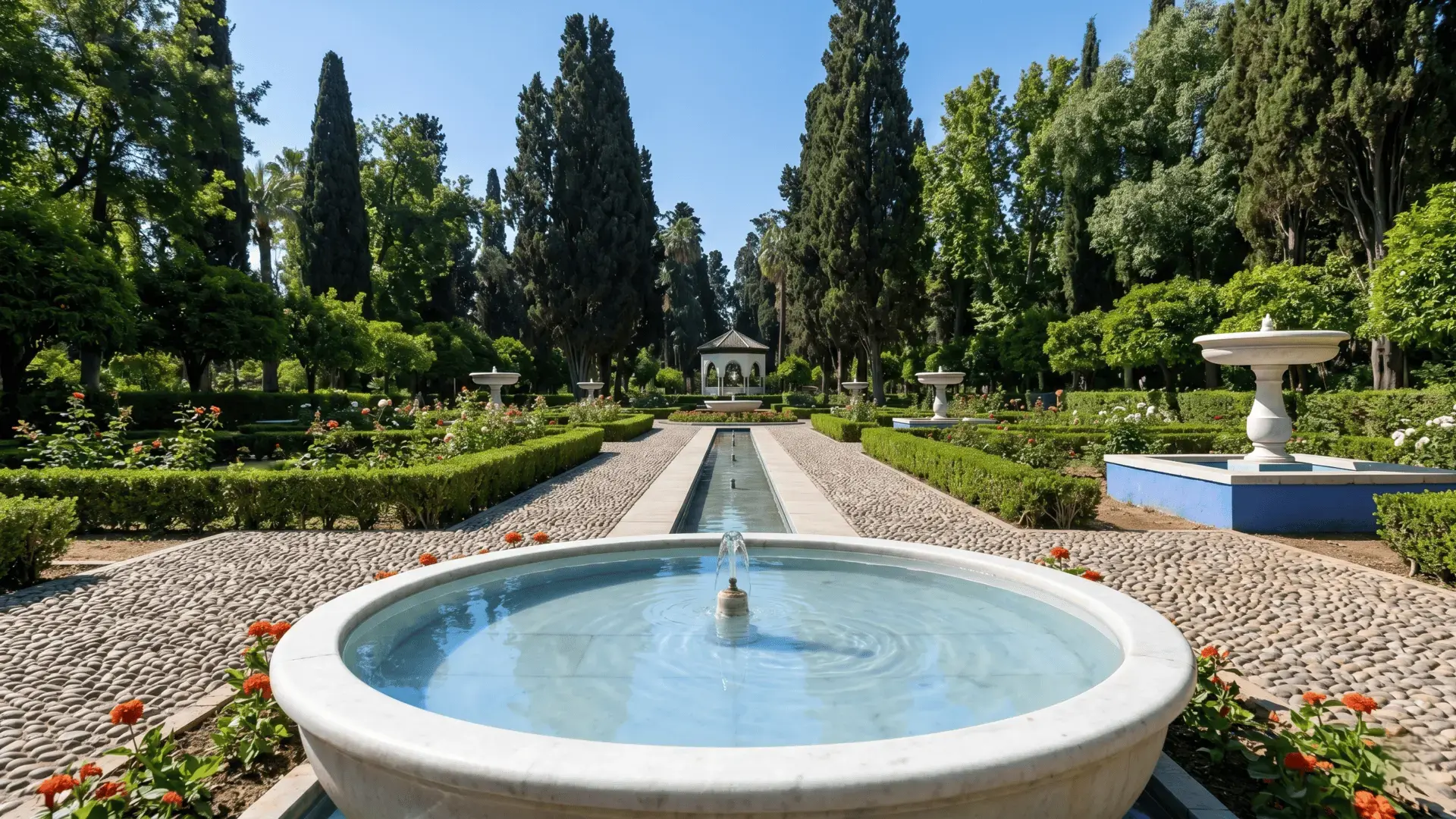 Jnan Sbil Gardens Fez Morocco | Beautiful Andalusian Fountains & Green Oasis Peaceful fountain in Jnan Sbil Gardens Fez Morocco with symmetrical hedges, roses, tall cypress trees, and a historic pavilion under blue sky